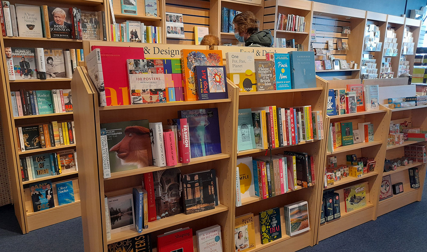The interior of Lyme Regis Bookshop, the Art and Design section, with a customer browsing the shelves